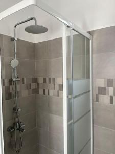 La salle de bains est pourvue d'une douche avec une porte en verre. dans l'établissement Πανοραμικό Ηλιοβασίλεμα, à Ios Chora