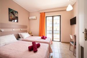 2 Betten in einem Zimmer mit roten Handtüchern darauf in der Unterkunft Prestige Holiday Apartments in Kos-Stadt