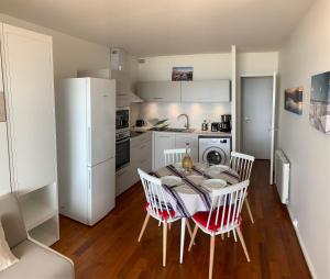 uma cozinha com uma mesa e cadeiras e um frigorífico branco em T2 Rés Océanides vue Océan, parking privé em Lacanau-Océan