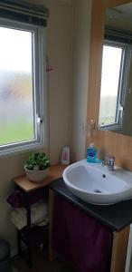 ein Badezimmer mit einem weißen Waschbecken und zwei Fenstern in der Unterkunft Beaches45 in Hythe