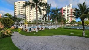 a park with a pool and palm trees and buildings at Alugar na Riviera Boulevard Flat in Riviera de São Lourenço