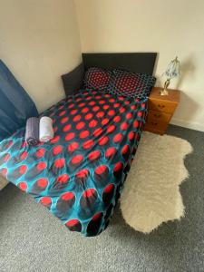 a bed with a blue and red comforter and a night stand at Quite Broad Rest 4 in Longford