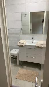 ein weißes Badezimmer mit einem Waschbecken und einem Spiegel in der Unterkunft T2 Rés Océanides vue Océan, parking privé in Lacanau-Océan