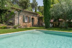 una piscina frente a una casa de piedra en Gites de la Villa Pergola en Salernes