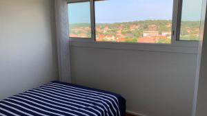 a bedroom with a striped bed and two windows at T2 Rés Océanides vue Océan, parking privé in Lacanau-Océan