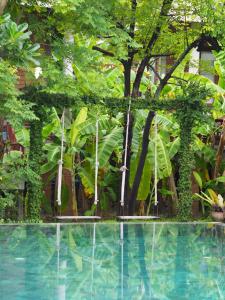 a swimming pool in a garden with trees at BaanSuk Sukhothai Resort in Sukhothai