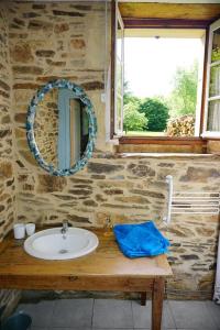 La salle de bains est pourvue d'un lavabo et d'un miroir sur un mur en pierre. dans l'établissement Domaine du Mas Coutant, à Sarlande