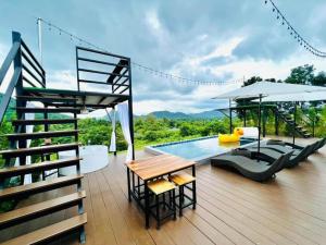 eine Terrasse mit einem Pool, einem Tisch und Stühlen in der Unterkunft เคียงดาว โฮมสเตย์ แก่งกระจาน in Ban Song Phi Nong