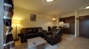 a living room with leather couches and a kitchen at Apartament Urocza in Szklarska Poręba