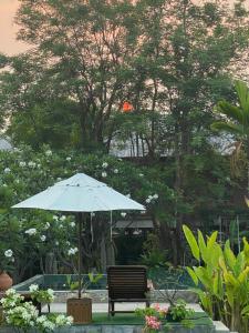 a bench with an umbrella in a garden at BaanSuk Sukhothai Resort in Sukhothai