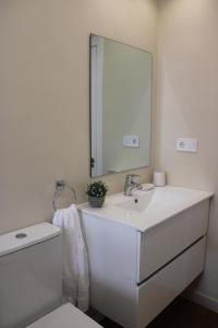 a white bathroom with a sink and a mirror at VIVIENDA VACACIONAL "EL CANXILÓN" Situada en Lastres - Zona Oriente de ASTURIAS - Casa independiente - Terraza con vistas al mar a 800 m de la playa in Lastres