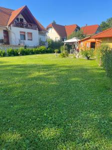 a yard of a house with a green lawn at Rege apartman in Alsóörs