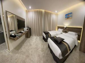 una camera d'albergo con due letti e una televisione di بارك المدينة للشقق المخدومة a Medina