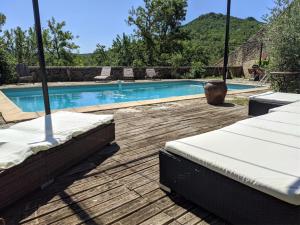 a swimming pool with two beds on a wooden deck at Gite Le Chevalier in La Répara