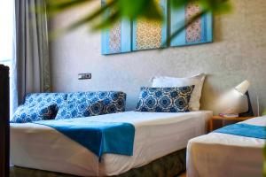 Route de miel في أغادير: غرفة نوم بسريرين مع وسائد زرقاء وبيضاء