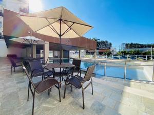 eine Terrasse mit einem Tisch, Stühlen und einem Sonnenschirm in der Unterkunft Spazzio diRoma c acesso ACQUA PARK SPLASH - Vacia Temporada in Caldas Novas