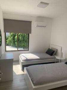 a bedroom with two beds and a large window at Prestige Worldwide Apartments in Ayia Napa