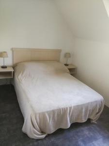 a white bed in a room with two tables at Domaine de l Emeraude in Le Tronchet