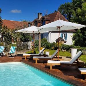- deux chaises longues et des parasols à côté de la piscine dans l'établissement Domaine du Mas Coutant, à Sarlande