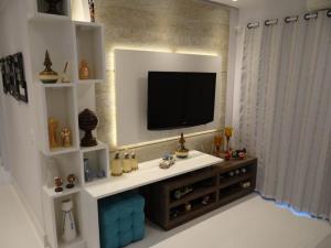 a living room with a television on a wall at Piscina Aquecida-Wifi-Net-Condomínio Reserva da Mata Módulo 8 Riviera de São Lourenço in Riviera de São Lourenço
