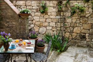 a patio with a table and chairs and a stone wall at Borgo Pignano in Pignano