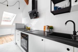 uma cozinha com armários brancos e um lavatório preto em Apartament na Jezuickiej em Lublin