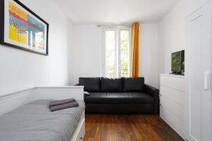 ein Wohnzimmer mit einem schwarzen Sofa und einem Fenster in der Unterkunft F1 Jean Jaurès 3G in Aubervilliers
