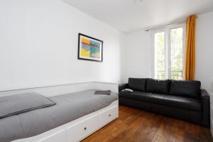 ein Schlafzimmer mit einem Bett und einem schwarzen Sofa in der Unterkunft F1 Jean Jaurès 3G in Aubervilliers
