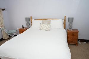 a bedroom with a white bed with two lamps and a chair at Character 2 double bedroom cottage in Shaftesbury in Shaftesbury