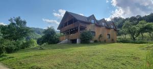 una grande casa su una collina con un prato di Cabana Suciu a Răchiţele