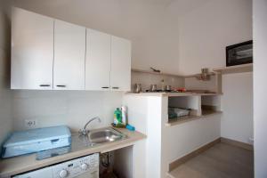 una pequeña cocina con armarios blancos y fregadero en Nonno Giovanni, en Gangi