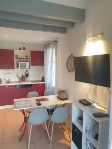 une cuisine avec une table et des chaises ainsi qu'une télévision dans l'établissement Agréable Villa en petite Camargue 35 m2 WIFI, à Gallargues-le-Montueux