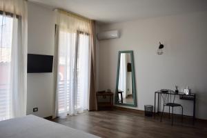 una camera da letto con pareti bianche, specchio e letto di Domus Solis a Pachino