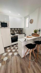 eine Küche mit weißen Schränken sowie einem Tisch und Stühlen in der Unterkunft Studio cosy Buttes-Chaumont in Paris