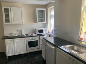 a kitchen with white cabinets and a sink and a microwave at Anfield view in Liverpool