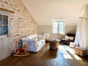 sala de estar con sofá blanco y pared de piedra en Charmant cottage à la campagne, en Marval