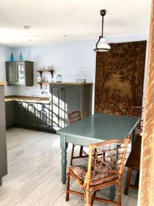 cocina con mesa verde y sillas en una habitación en Charmant cottage à la campagne, en Marval