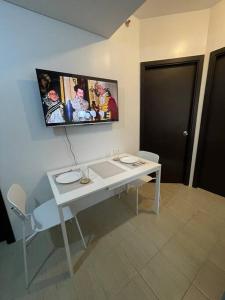 una camera con tavolo bianco e TV a parete di 2-bedroom Condo Unit a Manila