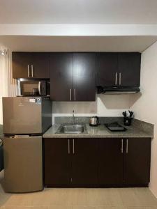 a kitchen with black cabinets and a stainless steel refrigerator at 2-bedroom Condo Unit in Manila