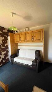 a bedroom with a bed and a chair and wooden cabinets at Le Cow'sy 1800 in Les Deux Alpes