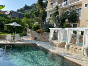 a swimming pool with chairs and an umbrella next to a building at A Vista in Parga