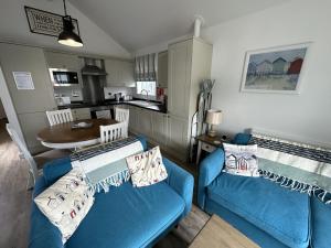 a living room with two blue couches and a kitchen at Azure Beach House - Part of the The Bay Filey Holiday Village with pool, gym and direct beach access, pub, restaurant, tennis and meadows walks in Filey