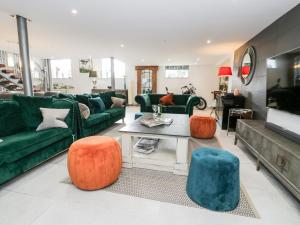 un soggiorno con divani verdi e sedie arancioni di Capel Mawr, Basement 19 a Caernarfon