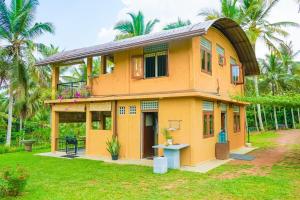 Casa amarilla con balcón en un patio en Amandawa Eco, en Gampaha