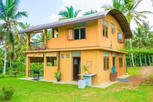 a yellow house with a balcony on a yard at Amandawa Eco in Gampaha