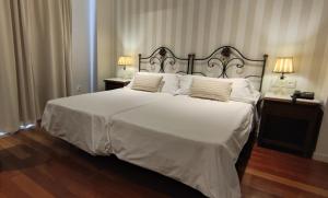 um quarto com uma grande cama branca e 2 candeeiros em Hotel Monumento Convento de San Benito em A Guarda