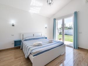 ein weißes Schlafzimmer mit einem Bett und einem großen Fenster in der Unterkunft Villa Lunu in Quartu SantʼElena