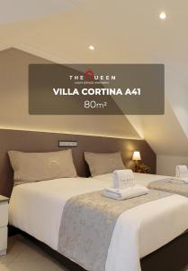 two beds in a room with a sign that reads the queen villa cortina at The Queen Luxury Apartments - Villa Cortina in Luxembourg