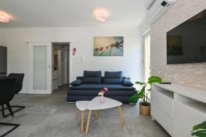 a living room with a blue couch and a table at Apartments Olive Garden 2 in Novalja