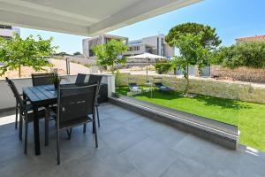 a patio with a table and chairs and a garden at Apartments Olive Garden 2 in Novalja